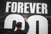 A fan adds a message to a memorial wall created near Anfield Stadium following the death of Liverpool soccer player Diogo Jota in Liverpool