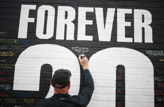 A fan adds a message to a memorial wall created near Anfield Stadium following the death of Liverpool soccer player Diogo Jota in Liverpool