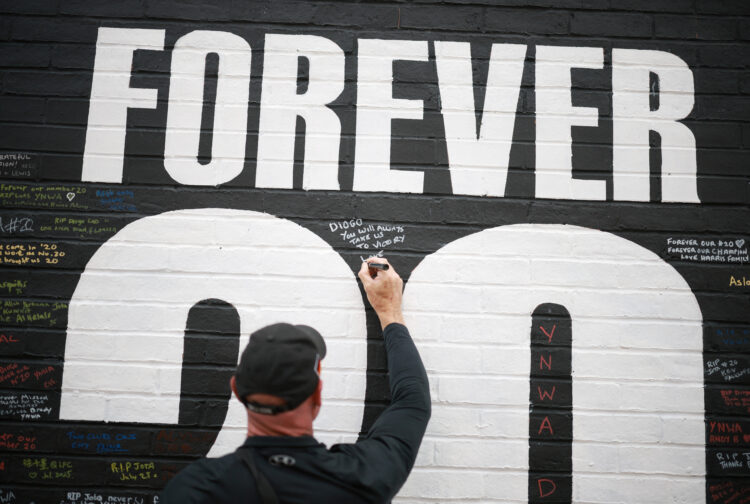A fan adds a message to a memorial wall created near Anfield Stadium following the death of Liverpool soccer player Diogo Jota in Liverpool